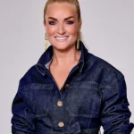 Samantha Steenwijk lachend in een donkerblauwe denim jumpsuit met gouden knopen en opvallende oorbellen.