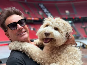 Gerard Joling poseert met zijn hond Buddy in een leeg stadion.