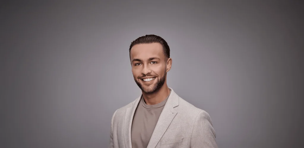 Portret van Delano Duncker in een lichtgrijs colbert tegen een grijze achtergrond.